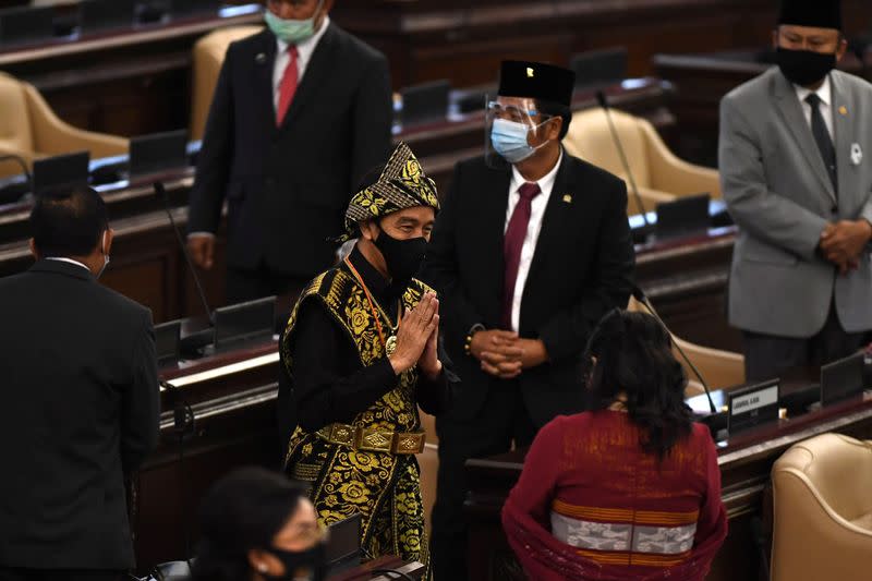 Indonesian President Joko Widodo wearing protective mask salutes to Indonesian parliament members as he arrives before delivering a speech ahead of the 75th Independence Day, at the parliament building in Jakarta