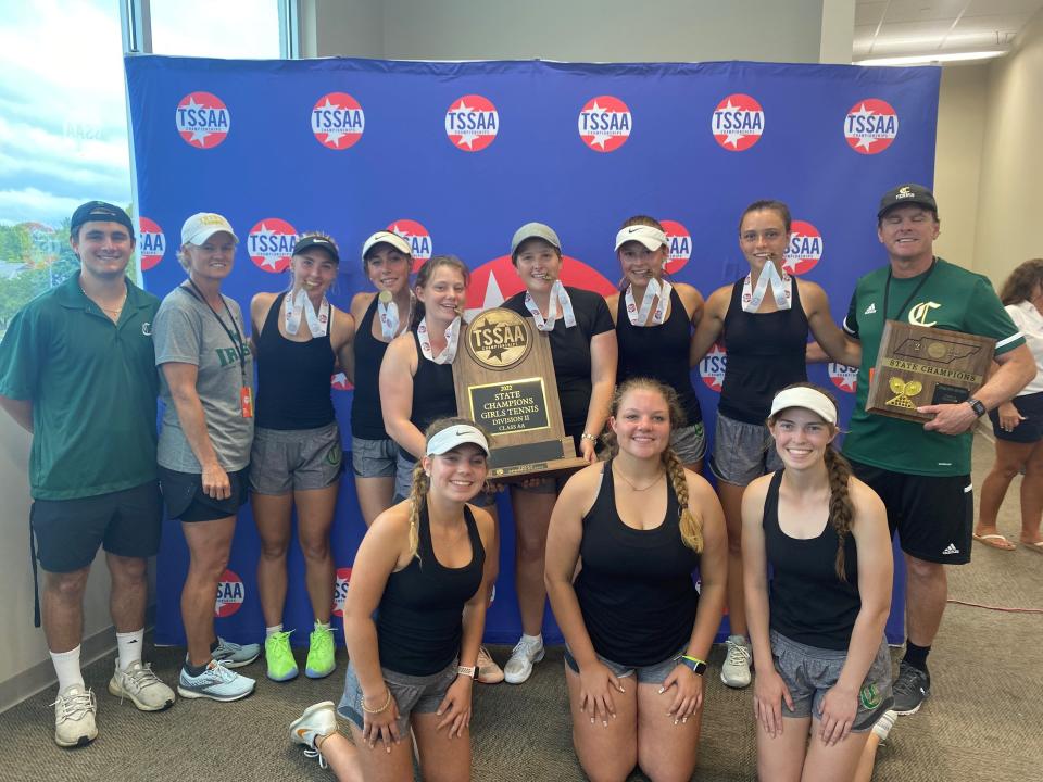 The Catholic girls tennis team, including coach Rusty Morris at top right, smile for the camera after winning the team title in Division II-AA on May 25, 2022.