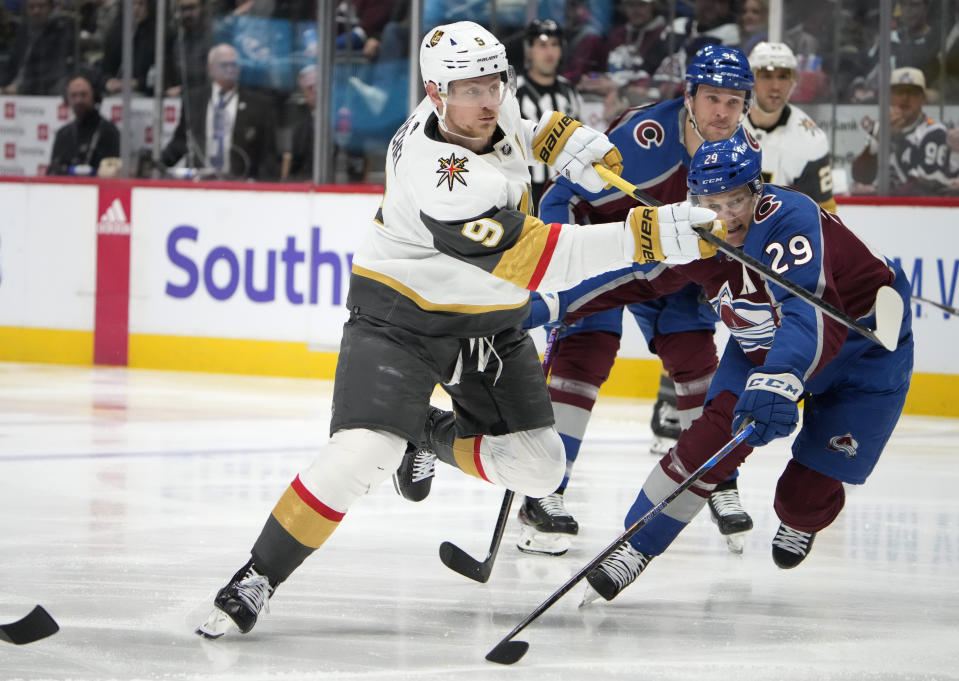 Vegas Golden Knights center Jack Eichel, left, shoots the puck as Colorado Avalanche center Nathan MacKinnon defends during the second period of an NHL hockey game Wednesday, Jan. 10, 2024, in Denver. (AP Photo/David Zalubowski)
