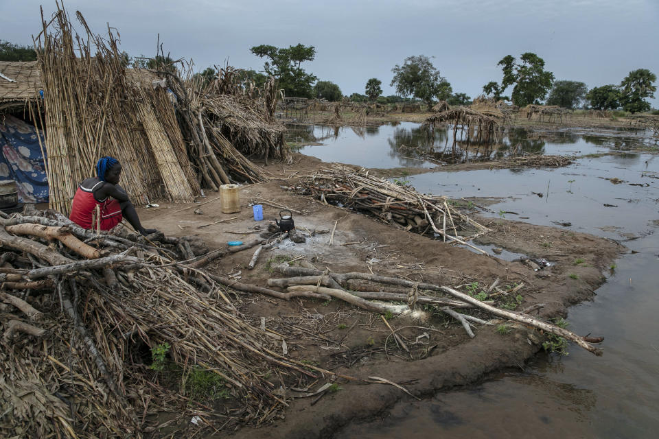 Nyibol Arop, a 27-years-old mother of five, boils her morning tea by the stagnant water that threatens her shelter, in Majak Awar village, Northern Bahr el Ghazal State, South Sudan, Wednesday, Oct. 20, 2021. "This flood is the worst of all," Arop said. The United Nations says the flooding has affected almost a half-million people across South Sudan since May. (AP Photo/Adrienne Surprenant)