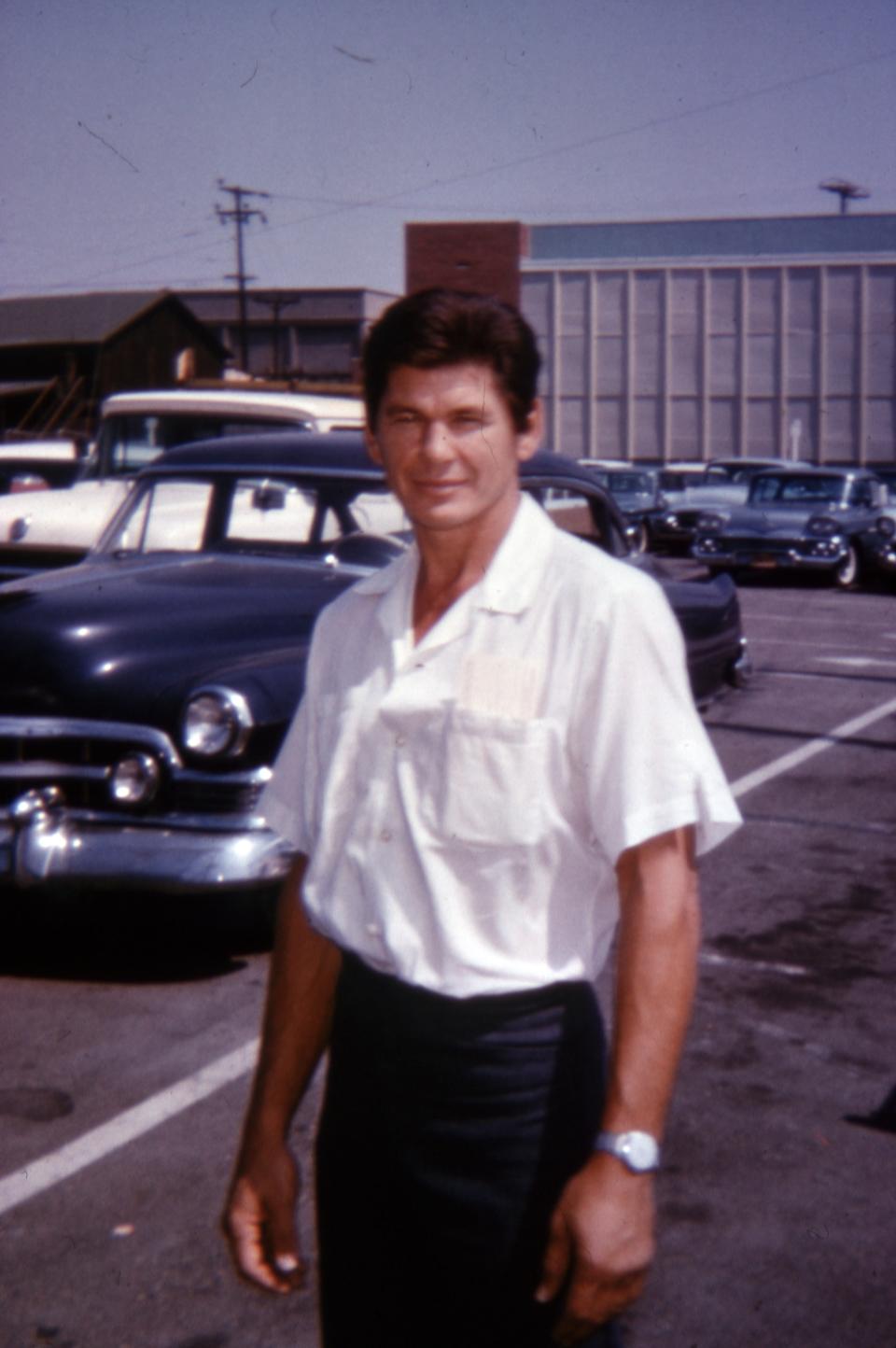 Charles Bronson stops for a photograph in a parking lot, possibly for the Hollywood unemployment office at 6725 Santa Monica Blvd.