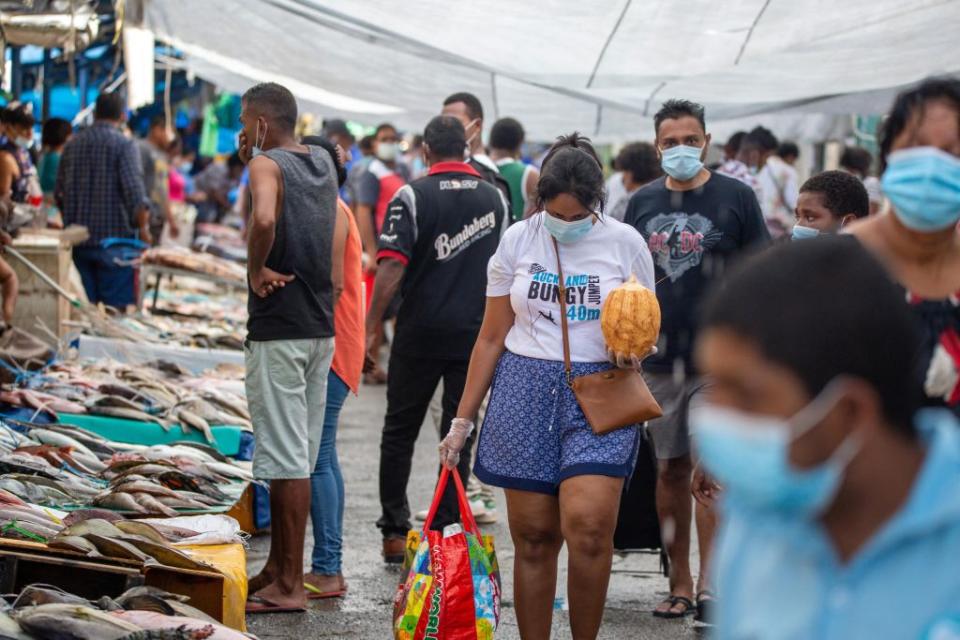 This picture taken on April 24, 2021 shows residents wearing face masks walking through the fish market in the Fijian capital Suva. Source: Getty