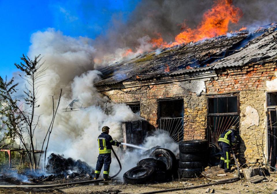 Ukrainian firefighters pushing out a fire in a warehouse after shelling in Kherson (UKRAINIAN EMERGENCY SERVICE/AFP)