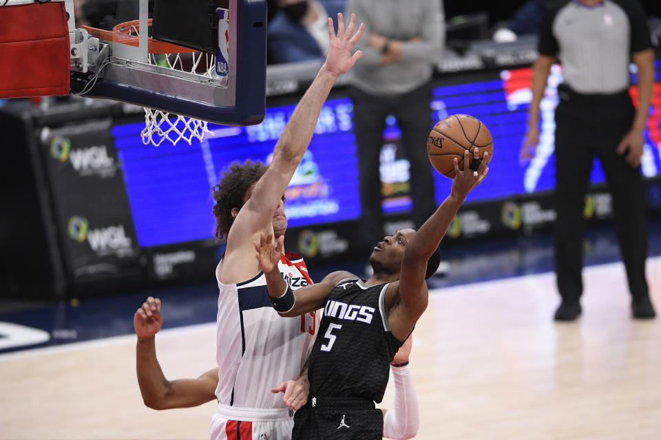Sacramento Kings guard De'Aaron Fox (5) goes to the basket against Washington Wizards center Robin Lopez, left, during the second half of an NBA basketball game, Wednesday, March 17, 2021, in Washington. (AP Photo/Nick Wass)