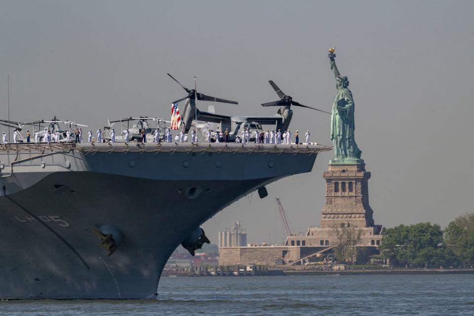 US Sailors and Marines stand on the flight deck of the USS Bataan, a Wasp-class amphibious assault ship, as it passes the Statue of Liberty during Fleet Week in New York Harbor on May 22, 2024.