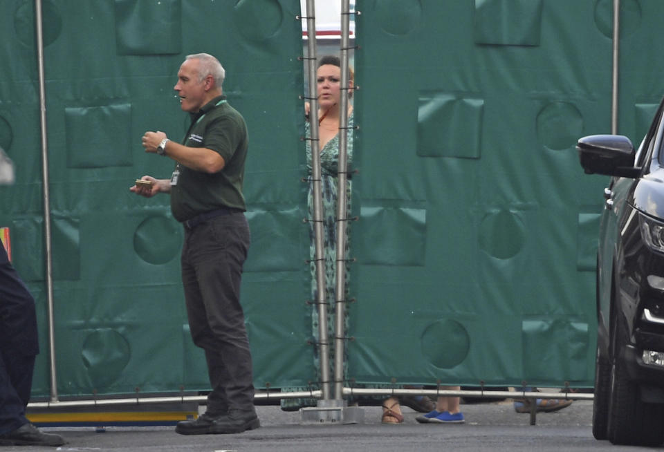 A woman looks through a gap in screens erected in Rollestone Street (Stefan Rousseau/PA via AP)