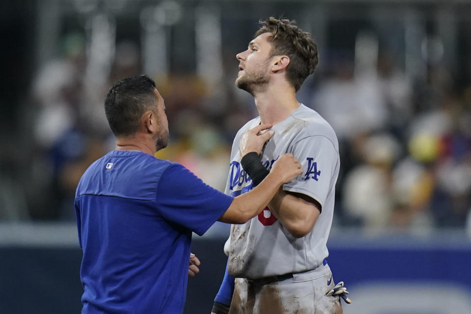 Los Angeles Dodgers' Trea Turner talks with a team official after getting hit by the ball while stealing second base during the fifth inning of the team's baseball game against the San Diego Padres, Friday, Sept. 9, 2022, in San Diego. (AP Photo/Gregory Bull)