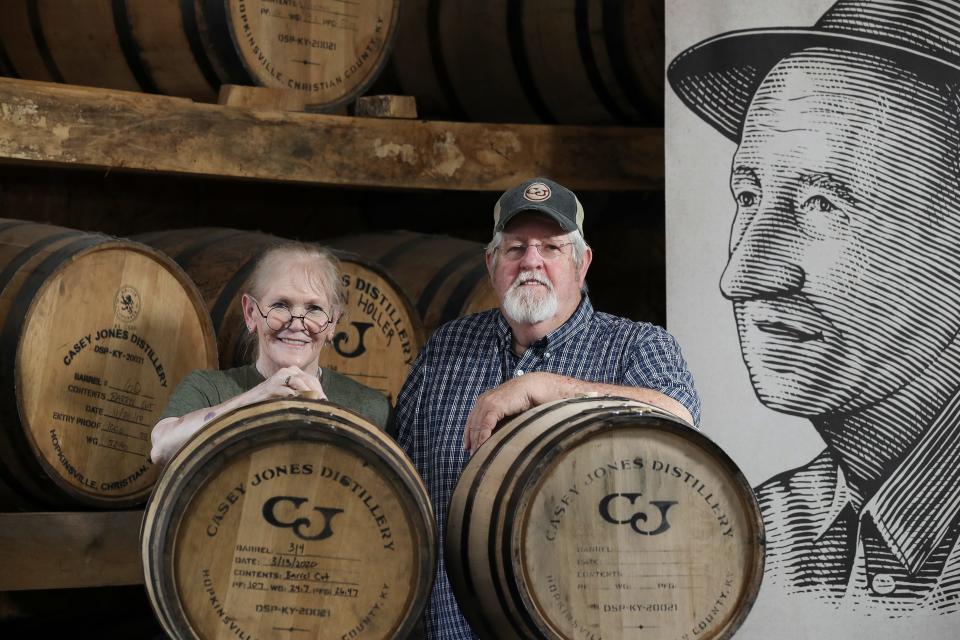 Arlon Casey Jones, right, and his wife Peg Hays at the Casey Jones Distillery in Hopkinsville, Ky. on July 25, 2022.  Jones' grandfather, Casey Jones, was a moonshine distiller who also built copper stills for other moonshine distillers during the prohibition era for which he spent some time in jail.  Arlon has carried on the tradition by distilling bourbon as well as other craft spirits at Casey Jones Distillery.   An image of his grandfather is in the background.