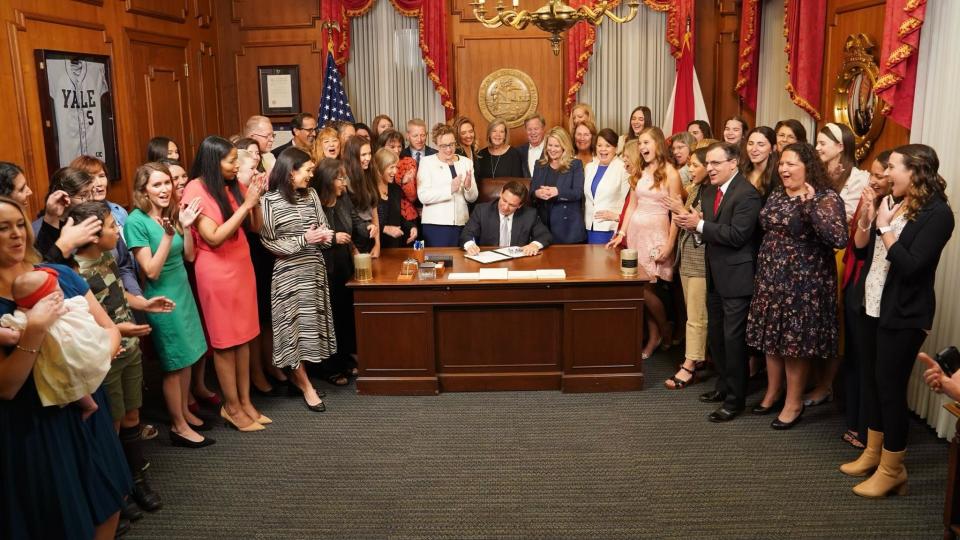 Florida Sen. Erin Grall, R-Fort Pierce, (center left, in white) looks over the right shoulder of Republican Gov. Ron DeSantis as he signs Senate Bill 300, also called the Heartbeat Protection Act, into law Thursday, April 13, 2023, in Tallahassee. The controversial legislation forbids the abortion of a fetus older than 6 weeks.