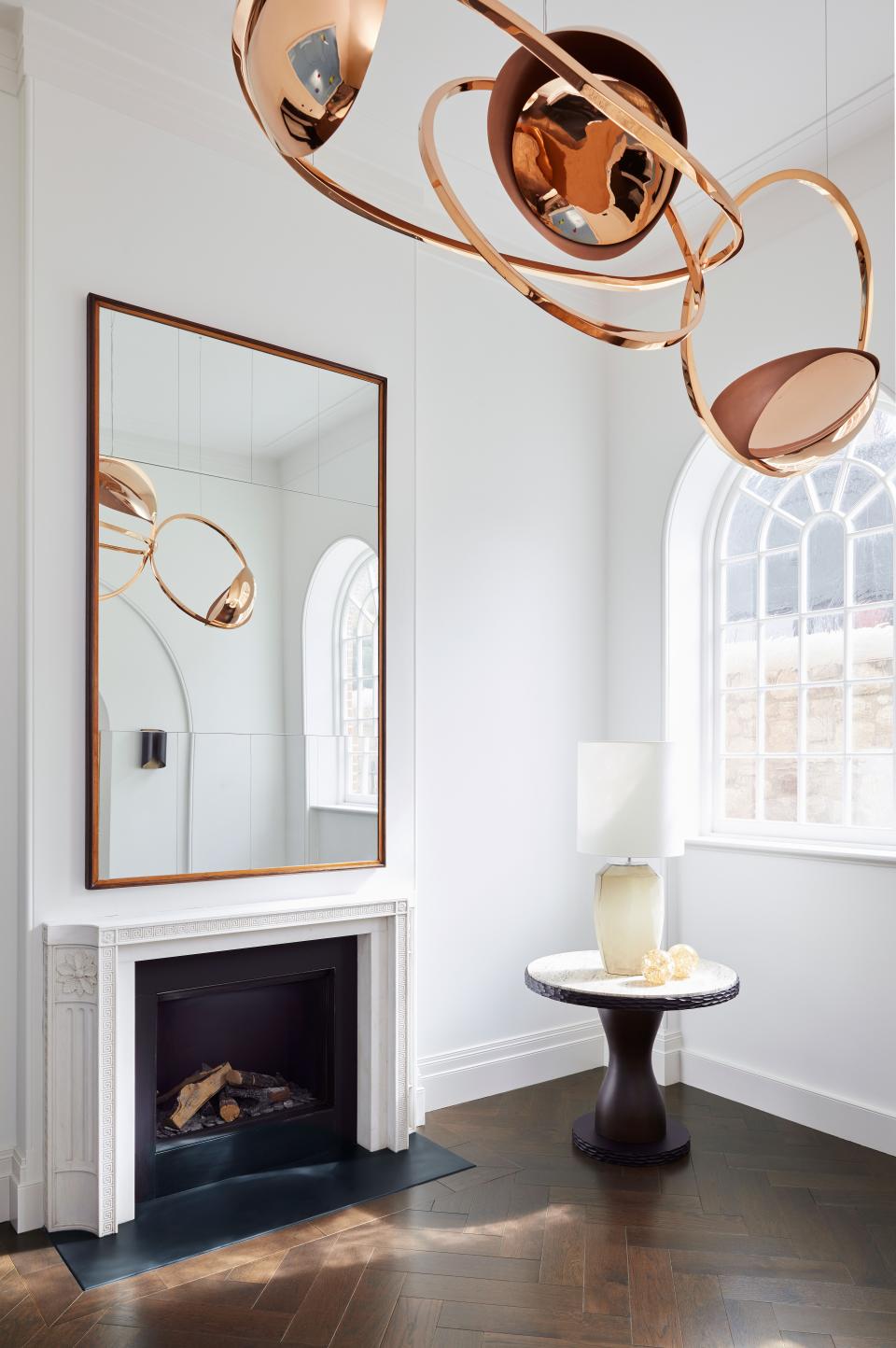 A sculptural pendant by Dublin-based designer Niamh Barry was purchased from Maison Gerard New York for this area of the house. The 1940s mirror is from London antique dealer Carlton Davidson while the round bronzed table is from Marc de Berny. The fireplace is a Soane design made by Ryan + Smith in Ireland.