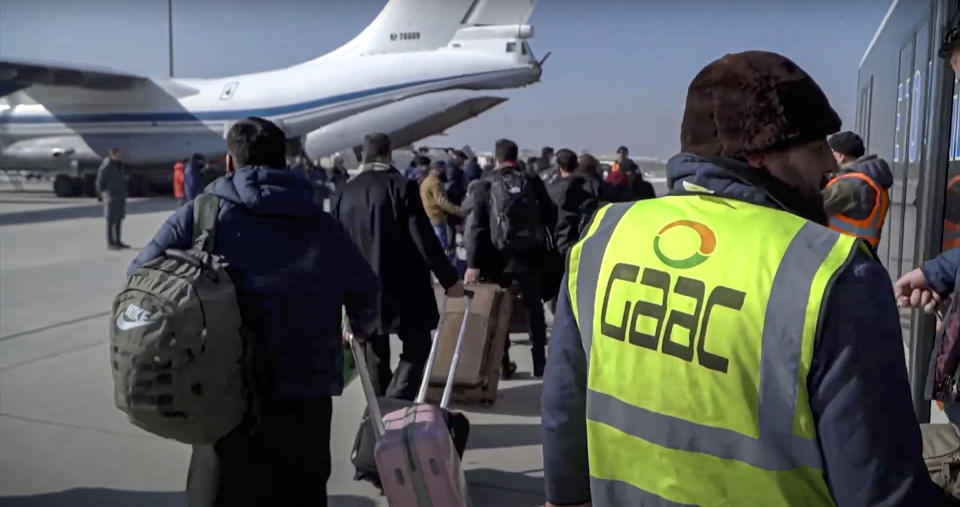 In this photo released by the Russian Defense Ministry Press Service, passengers gather to board Russian Military Il-76 cargo planes at the airport in Kabul, Afghanistan, Saturday, Dec. 18, 2021. Russian military transport planes have delivered a shipment of humanitarian supplies to Afghanistan and flew back 200 Russians, Afghan students and others. The Russian Defense Ministry said that three Il-76 cargo planes will make stopover in Tajikistan and Kyrgyzstan before flying to Moscow. (Russian Defense Ministry Press Service via AP)