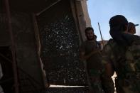 Rebels stand next to a metal door filled with shrapnel in the village of Al-Rami, near the town of Ariha, in the northwestern Syrian province of Idlib, on June 22, 2013. World powers supporting Syria's rebels decided on Saturday to provide them with urgent military aid so they can counter "brutal attacks" by the regime and "protect the Syrian people."