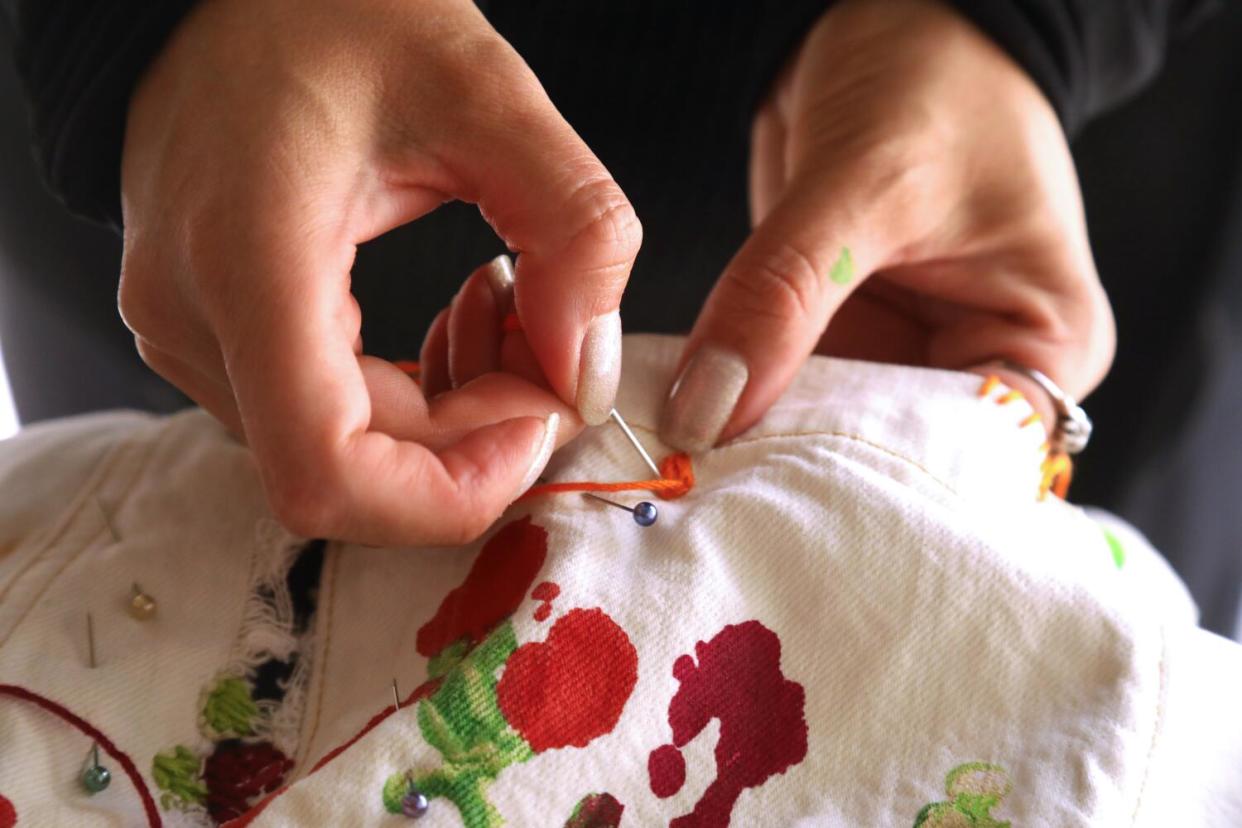 Betsy Flores of Other Lives Studio embroiders a pair of pants.