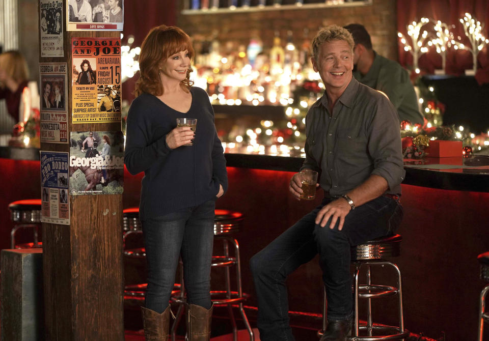 This image released by Lifetime shows Reba McEntire, left, and John Schneider from the holiday special "Reba McEntire's Christmas in Tune," premiering Nov. 26 on Lifetime. (Lifetime via AP)