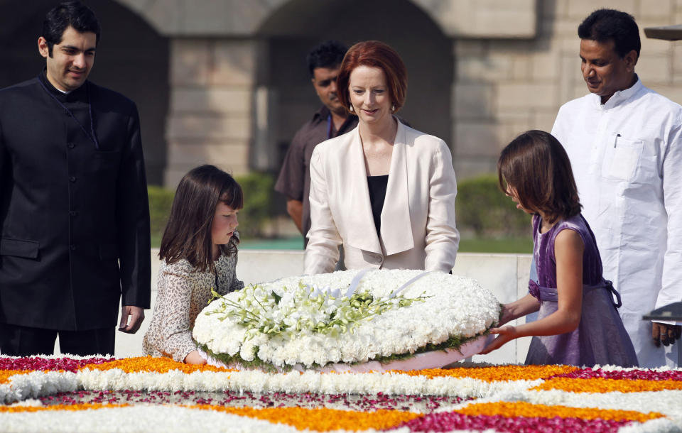 Australian Prime Minister Julia Gillard, center, accompanied by unidentified children pays floral respects at the memorial of Mahatma Gandhi in New Delhi, India , Wednesday, Oct. 17, 2012. (AP Photo/Mustafa Quraishi)