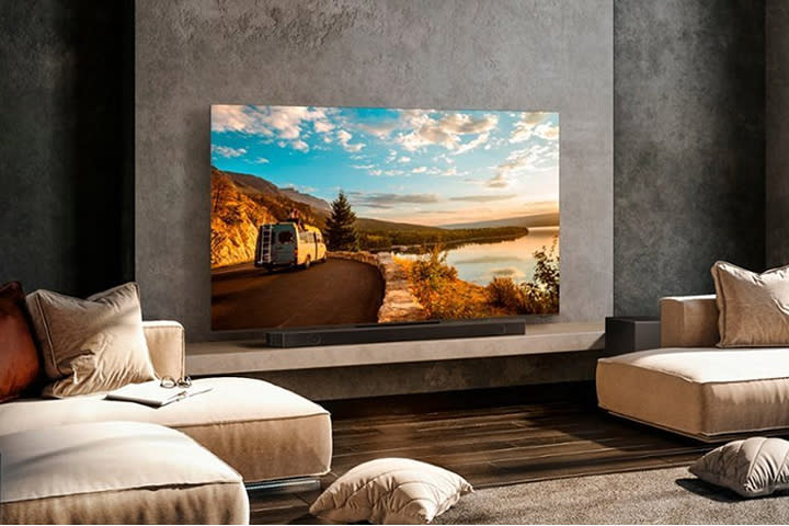 Samsung TV in a living room or hotel with couches surrounding it.