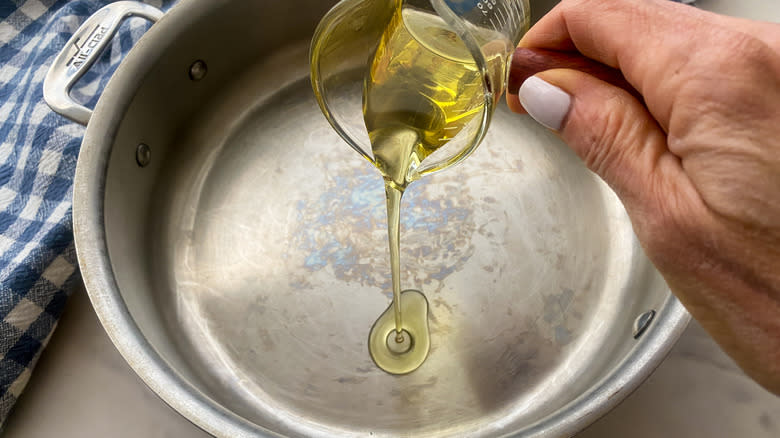 hand adding oil to a pan