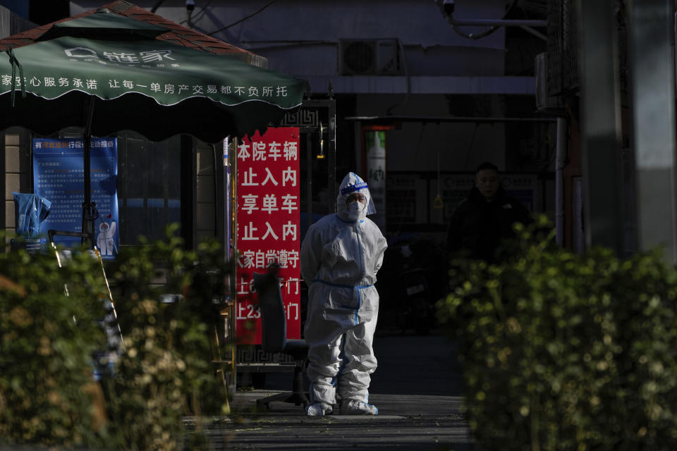 A security guard in protective gear stands watch at an entrance gate to a neighborhood in Beijing, Wednesday, Nov. 30, 2022. China's ruling Communist Party has vowed to "resolutely crack down on infiltration and sabotage activities by hostile forces," following the largest street demonstrations in decades staged by citizens fed up with strict anti-virus restrictions. (AP Photo/Andy Wong)