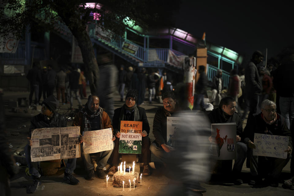 In this Wednesday, Jan. 22, 2020 photo, people hold placards as they sit near the protest site in New Delhi's Shaheen Bagh area, India. Muslim women are transcending the confines of their homes to lay claim to the streets of this nondescript Muslim neighborhood in the Indian capital and slowly transforming it into a nerve center of resistance against a new citizenship law that has unleashed protests across the country. The gathering at Shaheen Bagh started with a handful of women appalled by the violence at a nearby Muslim university during protests against the law on Dec. 15. Since then it has slowly morphed into a nationwide movement, with many women across the country staging their own sit-ins. (AP Photo/Altaf Qadri)t to the secular fabric of Indian society. (AP Photo/Altaf Qadri)