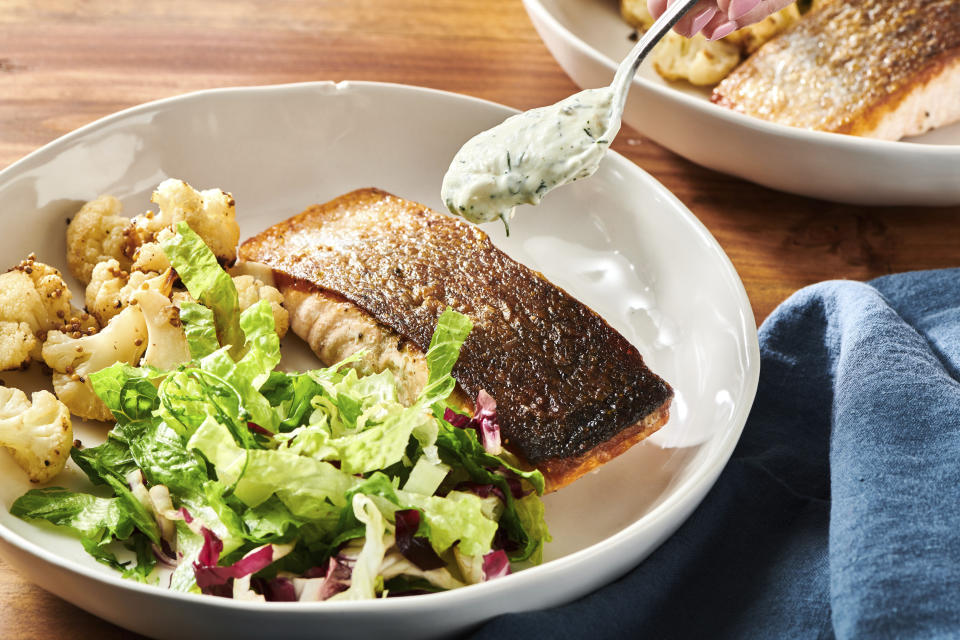 This October 2021 photo shows a recipe for crispy skinned salmon with dill sauce in New York. Pair your fish with a cool and creamy dill sauce and a couple of simple sides, and you have a restaurant-worthy meal in the comfort of home. (Cheyenne Cohen via AP)