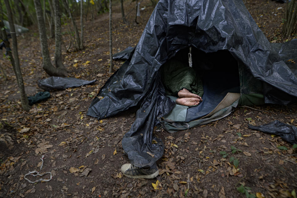 A migrant rests in a tent improvised from plastic sheets at a makeshift camp in a forest outside Velika Kladusa, Bosnia, Friday, Sept. 25, 2020.(AP Photo/Kemal Softic)