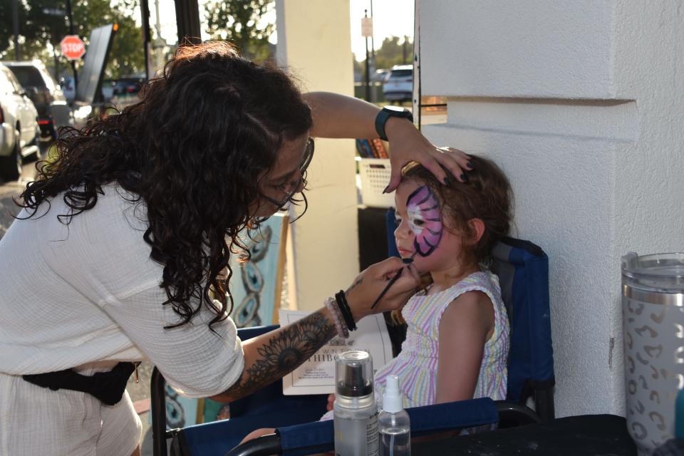 Shelby Toups, local artist with A Southern Thing, paints Charlott Lyons's, age 3, face during the Cajun Linen night in downtown Thibodaux, Aug. 11.