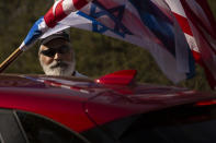 An Israeli supporter of the re-election of U.S. President Donald Trump waves American and Israeli flags from a car at a rally outside of the U.S. Embassy, in Jerusalem, Tuesday, Oct. 27, 2020. (AP Photo/Maya Alleruzzo)