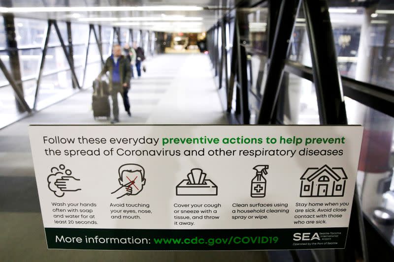 FILE PHOTO: A sign featuring preventative actions to stop the spread of Coronavirus is pictured at Seattle-Tacoma International Airport as passengers exit the main terminal, in SeaTac, Washington