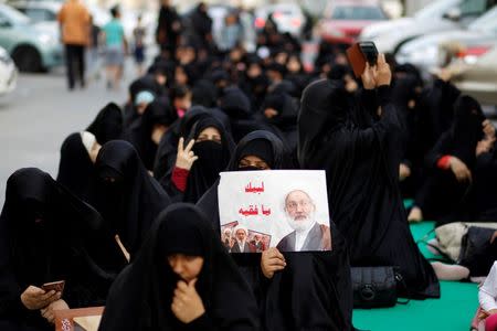 Supporters hold a poster with photo of Bahrain's leading Shi'ite cleric Isa Qassim during a sit-in in front of his home in the village of Diraz west of Manama, Bahrain June 21, 2016. Bahrain has stripped Qassim of his citizenship, state news agency BNA reported on Monday. REUTERS/Hamad I Mohammed
