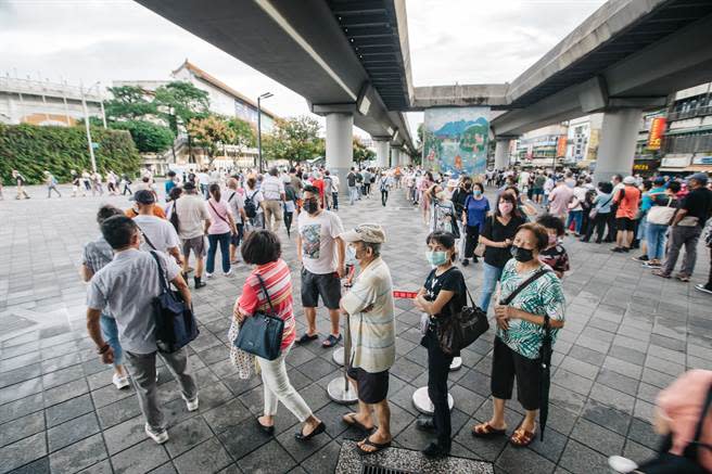 民眾13日冒雨前往場館接種疫苗；由於每日施打人數從六千人驟然上升至一萬三千人，場館外排隊人龍塞爆，民眾不滿動線紊亂，抱怨連連。（郭吉銓攝）