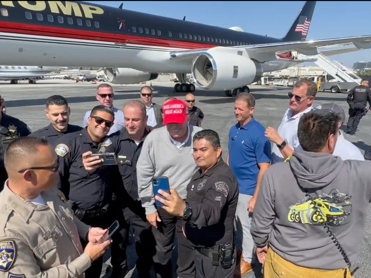 Mr Trump poses for photos with law enforcement officers in Los Angeles (  Dan Scavino Jr. / Twitter)