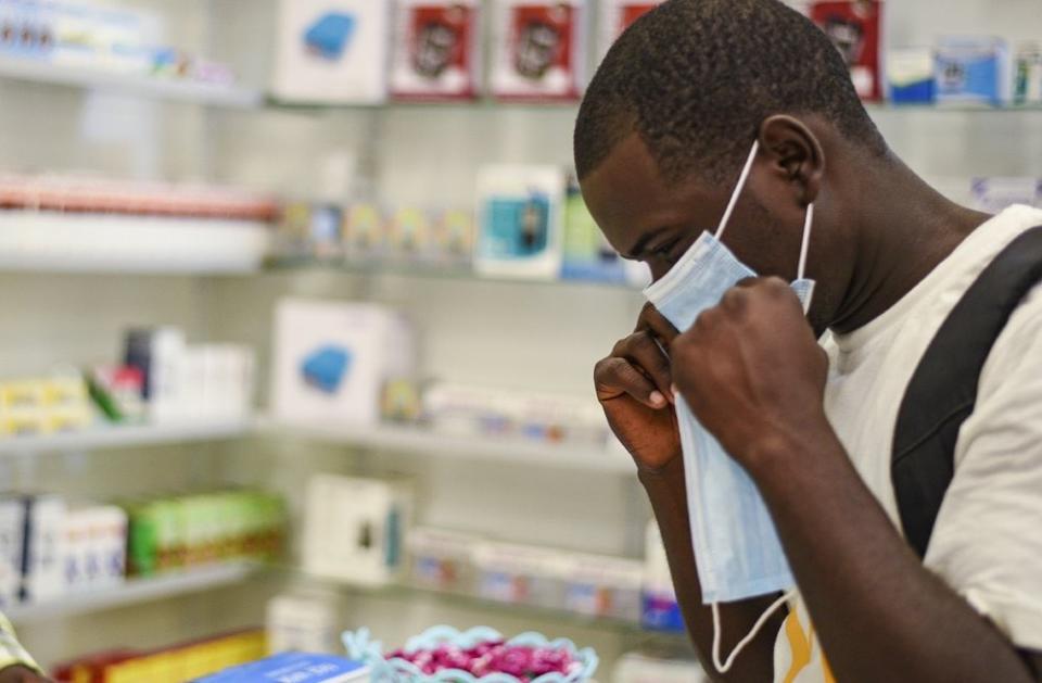 In this Feb. 6, 2020, file photo, a man tries on a face mask at a pharmacy in Kitwe, Zambia. (AP Photo/Emmanuel Mwiche, File)