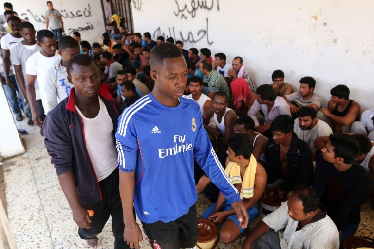 Migrants rescued by the Libyan coastguard after their boat sank sit in a security center between the coastal cities of Subrata and Zuwara, on August 28, 2015