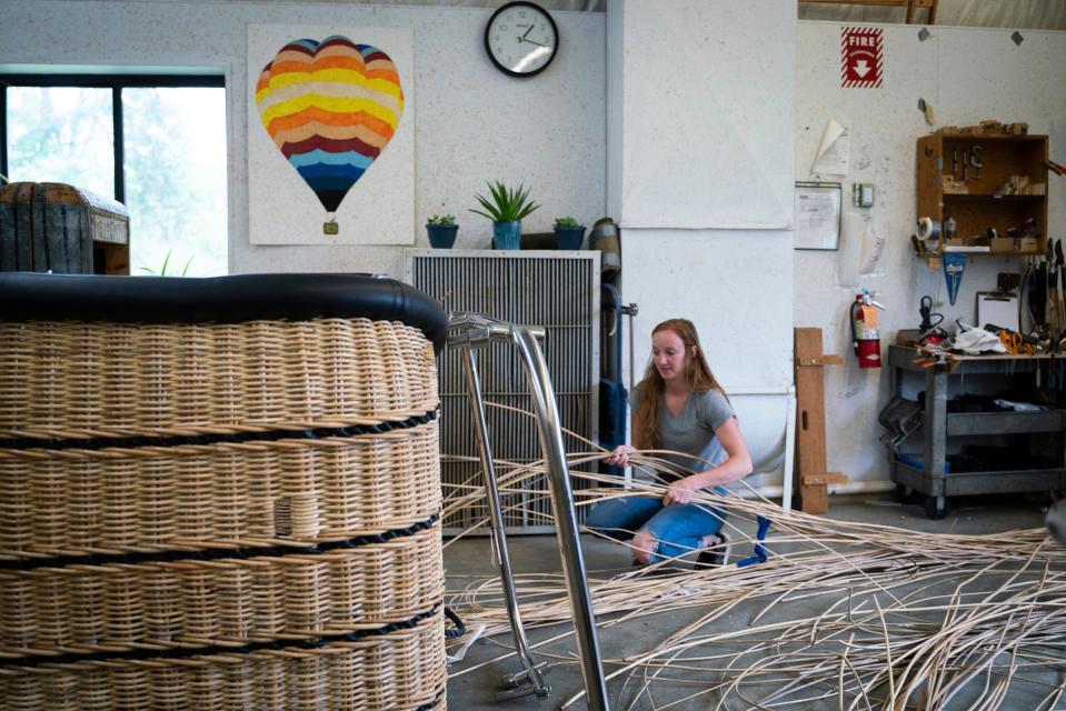 Basket weaver Brittany Wollet, 23, of Jackson, organizes wicker to finish weaving a basket for the Alpha 5 Project hot air balloon at Cameron Balloons in Dexter on Friday, August 11, 2023. Wollet said the project has taken her and her weaving partner Sabrina Ellis over a month to complete.