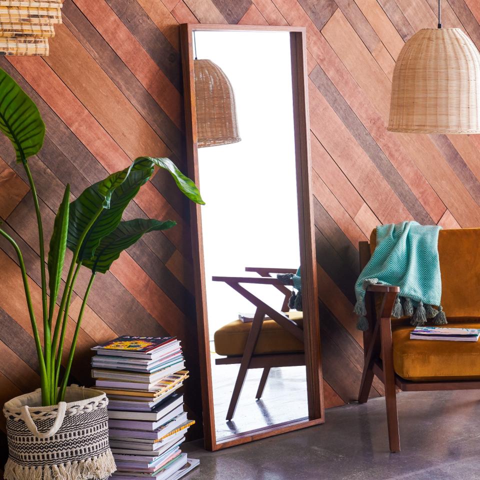 rectangular leaning mirror with wood frame against a wall