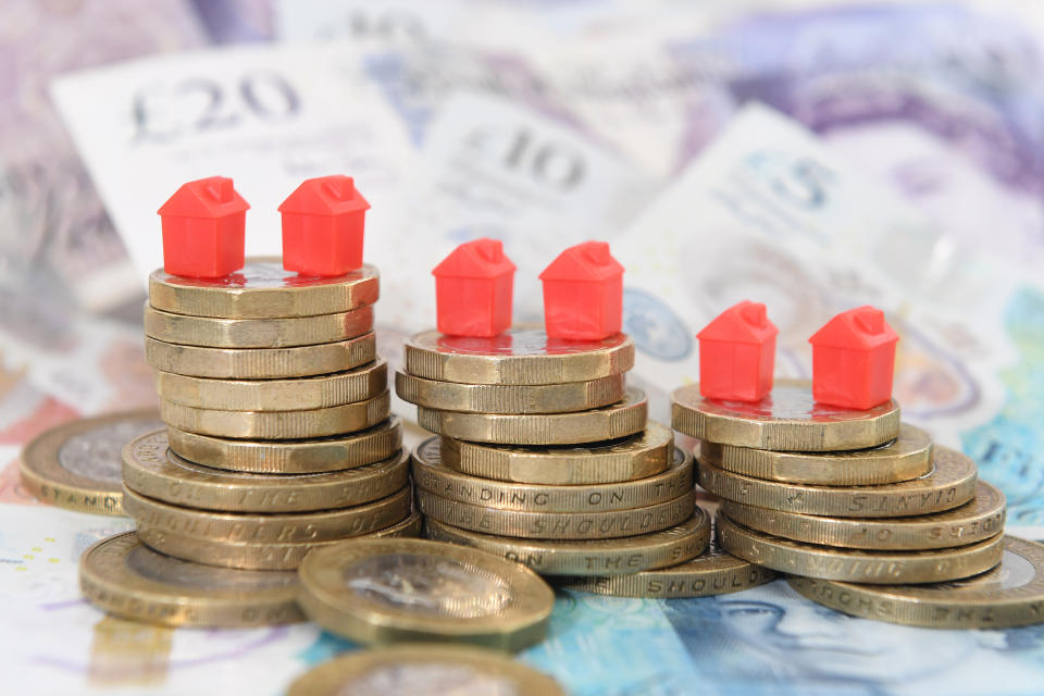 Model houses on a pile of coins and bank notes, signifying UK house prices