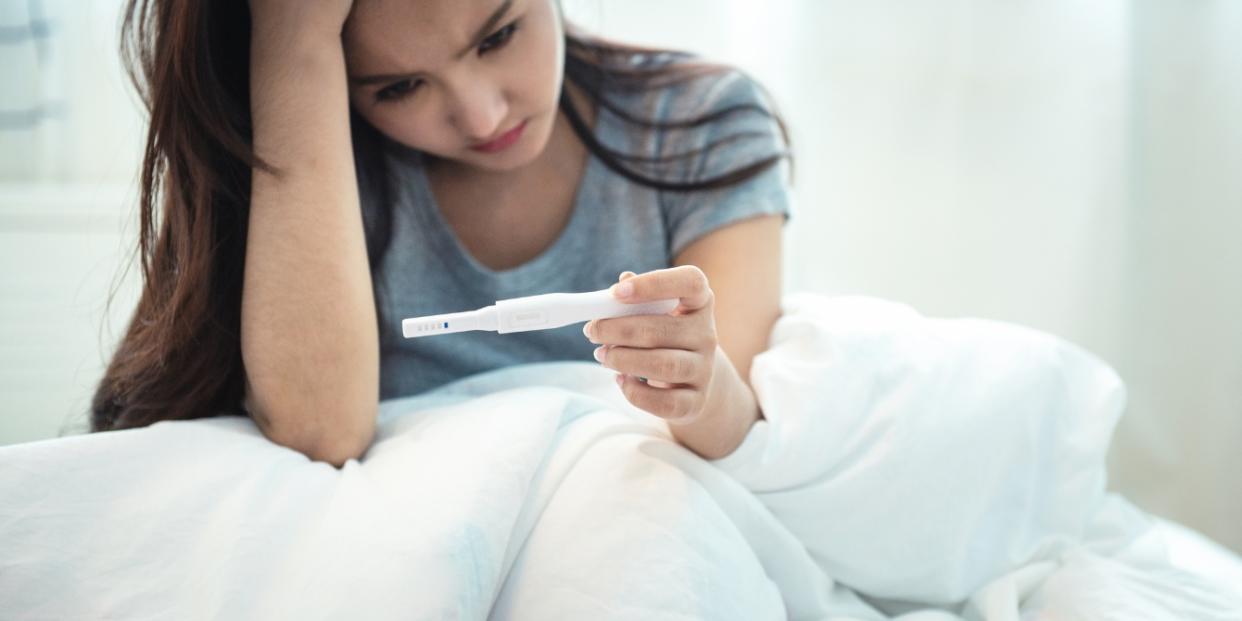 sad woman holding pregnancy test - how common is secondary infertility