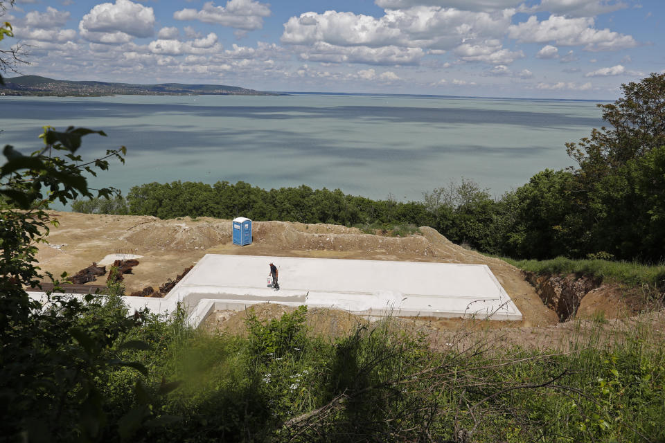 A worker walks at the construction site near Lake Balaton on the peninsula of Tihany, Hungary - a UNESCO world heritage site - on May 18, 2021. Lake Balaton is the largest lake in Central Europe and one of Hungary's most cherished natural treasures. But some worry that the lake's fragile ecosystem and the idyllic atmosphere of the quaint villages dotted along its banks are in danger because of speculative developments. (AP Photo/Laszlo Balogh)