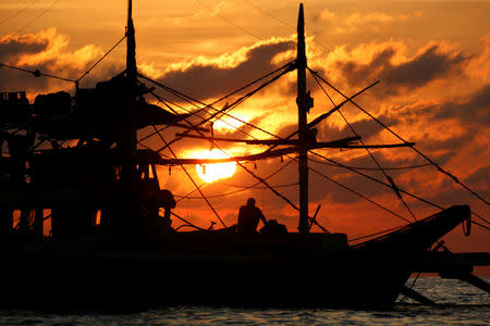 A Philippine fisherman sits on his boat during sunset at the disputed Scarborough Shoal April 5, 2017. Picture taken April 5, 2017. REUTERS/Erik De Castro