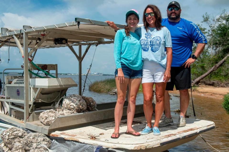 Juliana Ladner, left, whose father allowed for his land to be used for a staging site for the living shoreline project, Cecelia Cenac, part owner of C. Cenac & Co and French Hermit Oyster Co., and Jerry Atkinson, right, who works with the Mississippi Gulf Fishing Banks, pose for a photo on an oyster boat Cenac lent for the project on Tuesday, July 23, 2024. Ladner, Cenac and Atkinson all volunteered time and resources to help with the living shoreline project, which will help prevent erosion and create an oyster reef ecosystem.