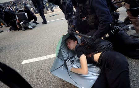 A person lies down as he's being detained by riot police officers while anti-government protesters demonstrate in Admiralty district, Hong Kong