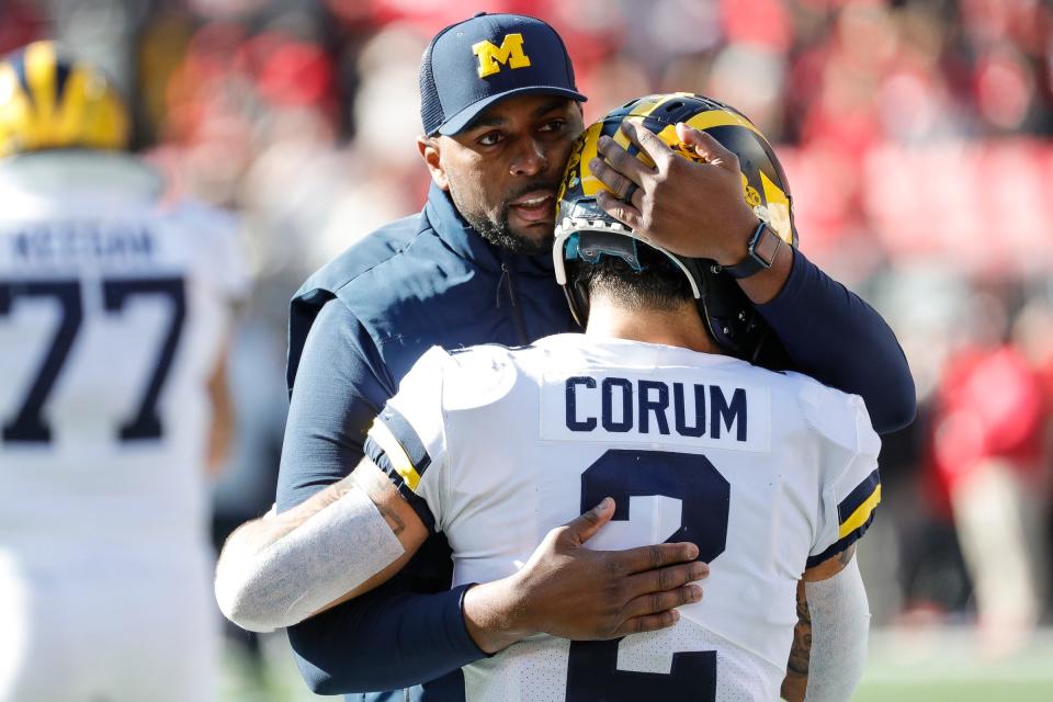 Michigan running back Blake Corum is hugged by co-offensive coordinator Sherrone Moore during warmups  against Ohio State.