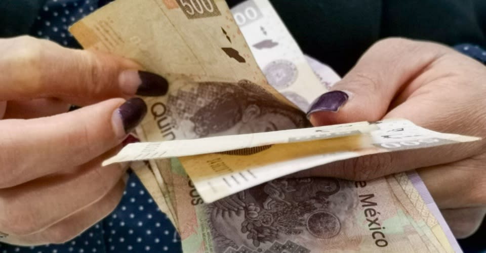 Manos contando billetes de 500 pesos