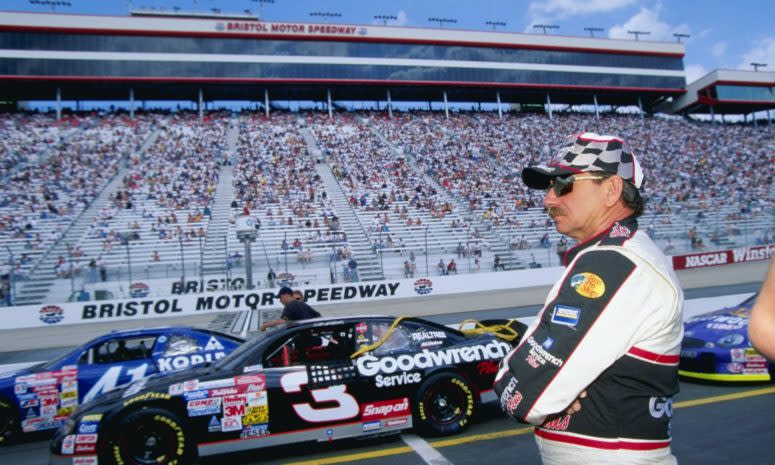 Dale Earnhardt Sr. stares to his left while standing in front of his race car.