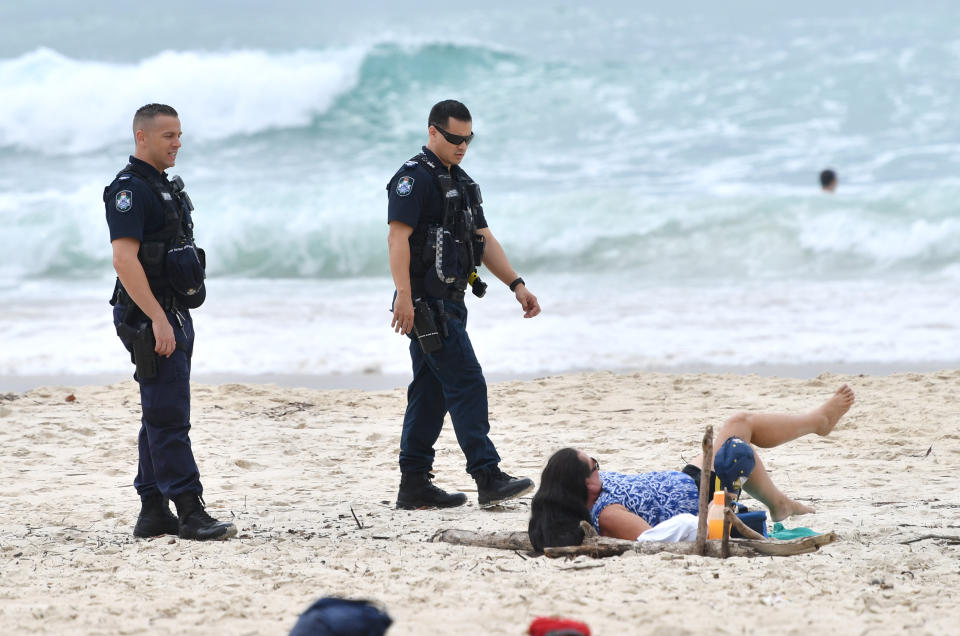 Queensland Police are seen talking to a sunbather on the beach at Burleigh Heads.