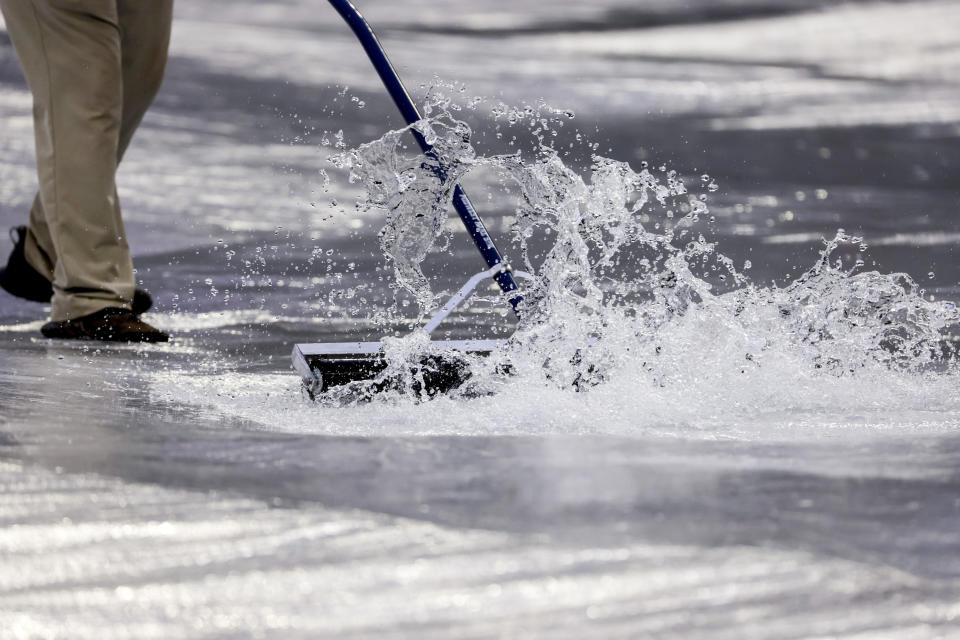 A grounds crew member prepare the field after a thunderstorm passes through before a baseball game between the Atlanta Braves and the Arizona Diamondbacks, Saturday, July 30, 2022, in Atlanta. (AP Photo/Butch Dill)