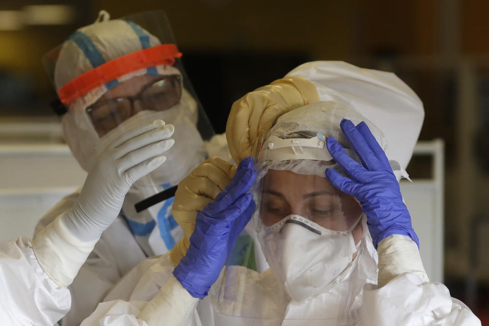 Healthcare workers attending to COVID-19 patients adjust their protective gear in an intensive care unit (ICU) at Na Bulovce hospital in Prague, Czech Republic, Thursday, Oct. 1, 2020. A record surge of new coronavirus infections in the Czech Republic in September has been followed by a record surge of those hospitalized with COVID-19. The development has started to put the health system in the country under serious pressure for the first time since the pandemic hit Europe. (AP Photo/Petr David Josek)