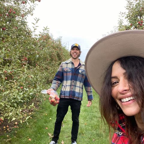 <p>Adam Demos Instagram</p> Adam Demos and Sarah Shahi take a picture together at an apple orchard.