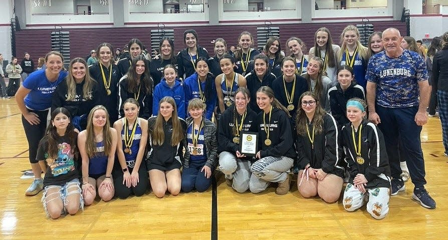 Athletes and coaches from the Lunenburg girls' indoor track team celebrate winning the Mid-Wach C Championship on Friday at Fitchburg High.
