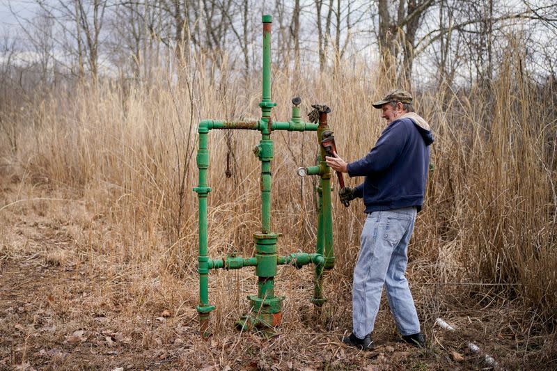 Hanson Rowe, a landowner who blames a leaky gas well on his property for health problems, tightens a valve on an abandoned gas well on his property in Salyersville